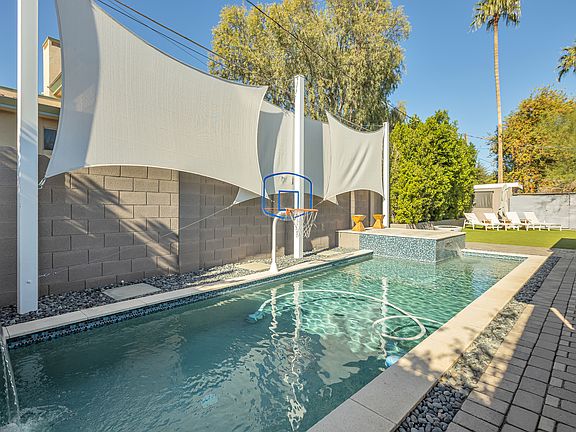 Expansive private backyard featuring a sparkling pool with dual waterfalls and mature ficus trees for exceptional privacy