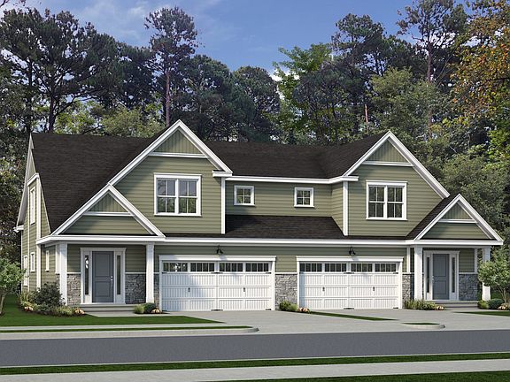 A two-story duplex house with green exterior, white trim, and dark grey roof. Each unit has a two-ca