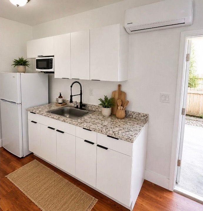 Streamlined kitchen with stone-look counters, deep sink and gooseneck faucet, plus fridge, microwave and ample cabinetry.