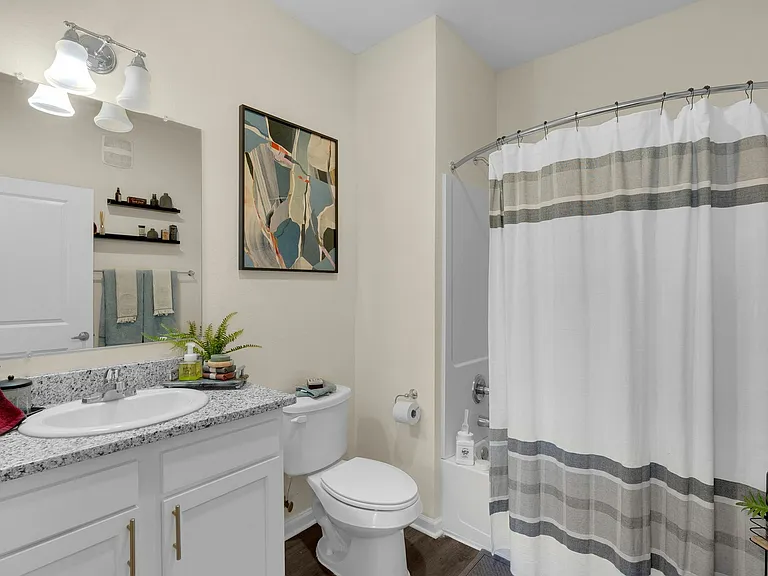 Relax in a modern bathroom with stylish hardwood-style flooring at The Flatts Starkville, offering premium student housing