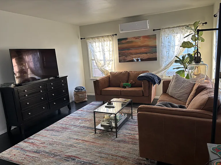 Bright and inviting family room with ample space, abundant natural light, and elegant dark wood flooring throughout.
