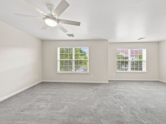 Spacious primary bedroom with two windows, abundant natural light and a modern ceiling fan.