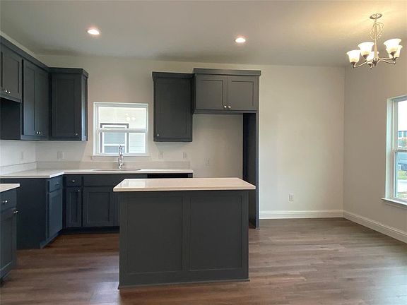 Kitchen featuring dark wood-type flooring, recessed lighting, a chandelier, a center island, and decorative light fixtures