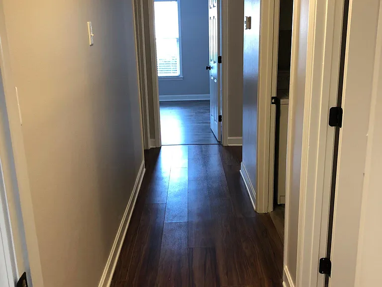 Hallway leading from bedroom to bedroom with laundry and second bathroom off to the right and left