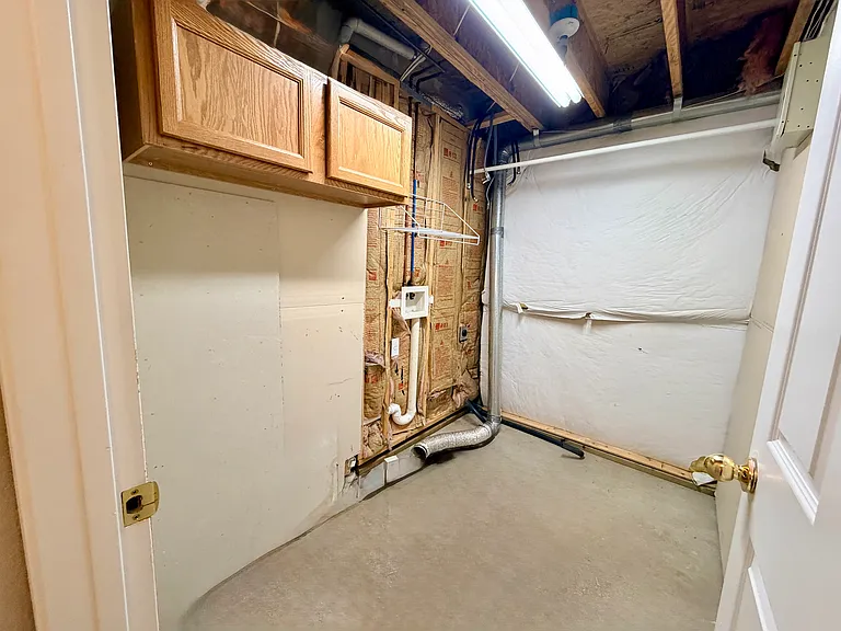 Dedicated laundry room with washer and dryer hookups, overhead cabinetry, and additional storage space conveniently located within the lower level.