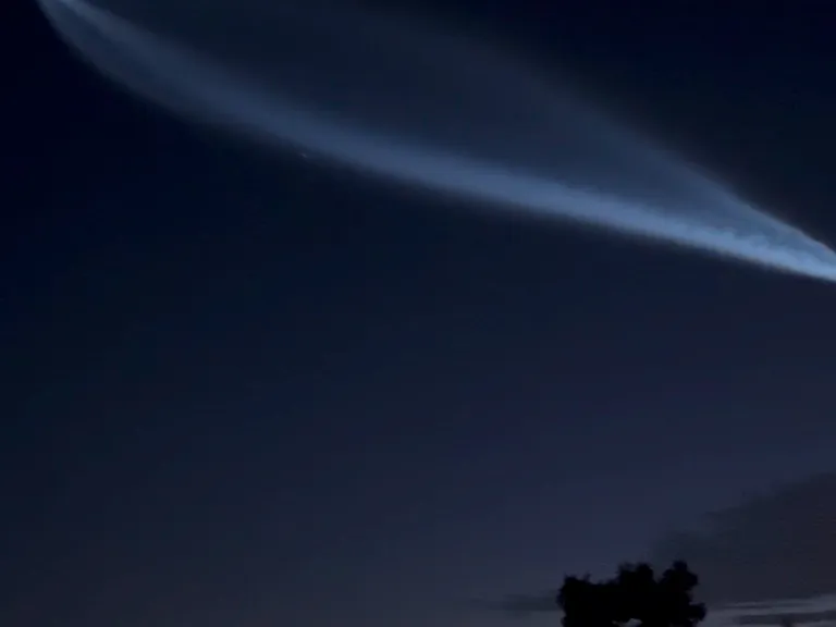 Space-X passing over the night sky with the hillside lights in the background.