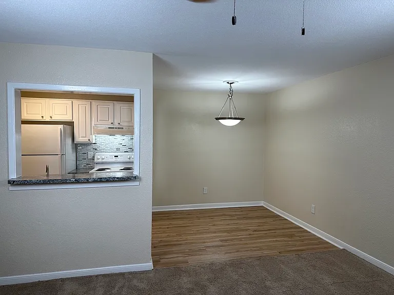 Cozy apartment interior featuring a modern kitchen with a pass-through counter, adjacent to a dining area with elegant lighting. Cozy apartment interior featuring a modern kitchen with a pass-through counter, adjacent to a dining area with elegant lightin