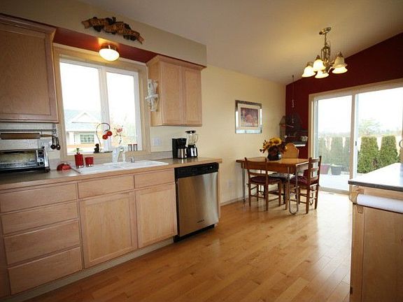 Kitchen with wood floors and dining area with sliding door to deck and back yard.