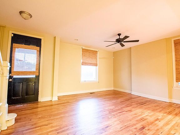 Sunny living room with hardwood floors, blinds and ceiling fan.