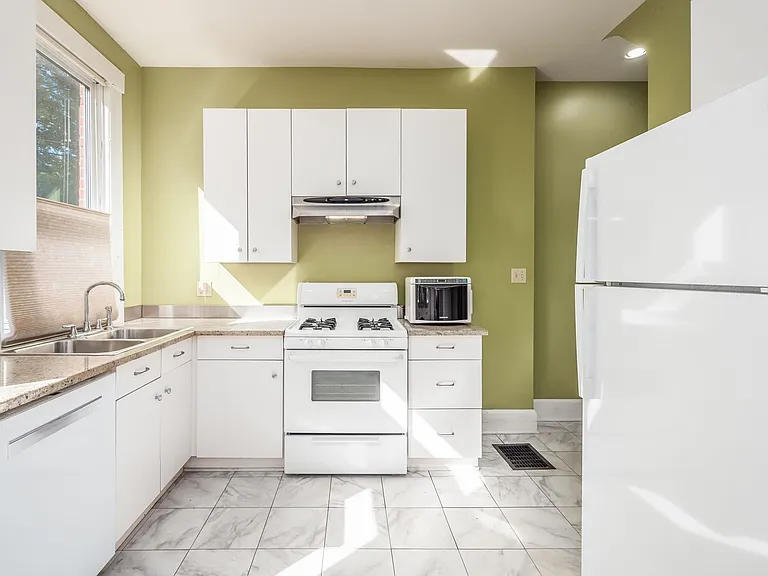 Kitchen with all white cabinetry and appliances, refrigerator is new in 2022. Paint color has been updated to neutral.