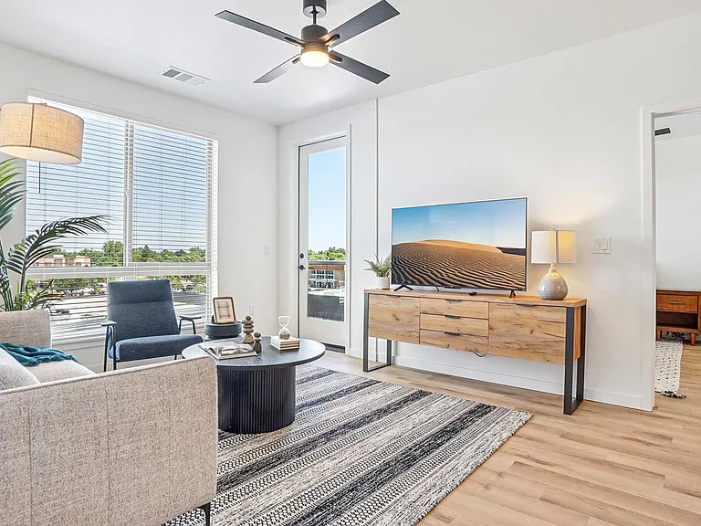 Relax in a light-filled living space featuring modern furnishings, wood-style flooring, oversized windows, and private balcony access.