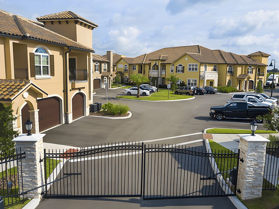 Gated entrance to Portofino at ChampionsGate with view of Mediterranean-style townhomes and landscaped drive.