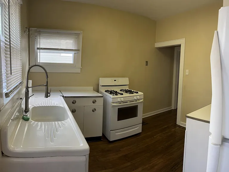 Kitchen, view 1 - original, retro cabinets and cast iron sink. New dishwasher is being installed to the left of the range.