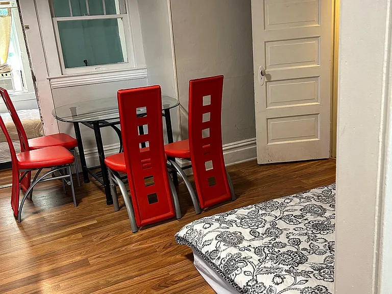 Furnished bedroom with hardwood floors, a small dining table and chairs, and a window for natural light.