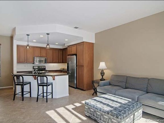 view from stairs looking at kitchen with island. To the left is a dining area