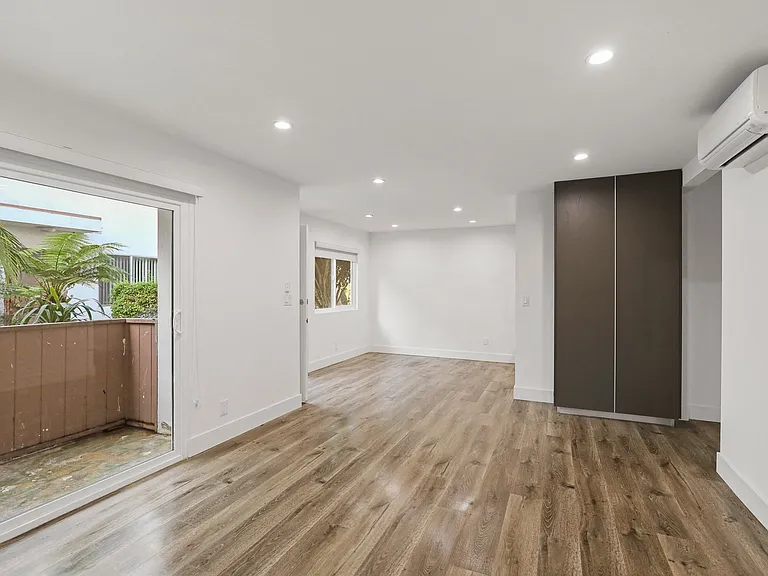 Living Room Area with Vinyl Flooring, Wall Heater, and Sliding Glass Door to Access Patio