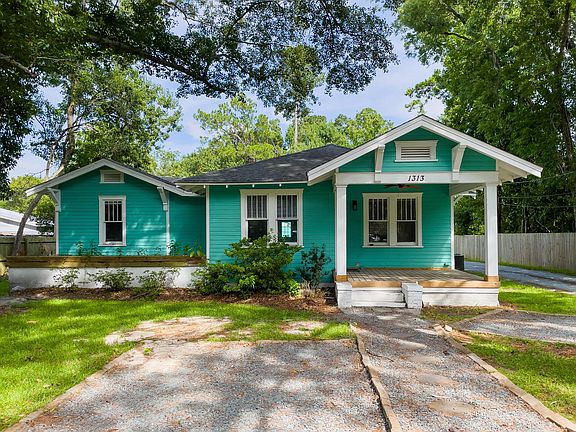 Front of home depicting covered front porch and 2 gravel parking spaces.