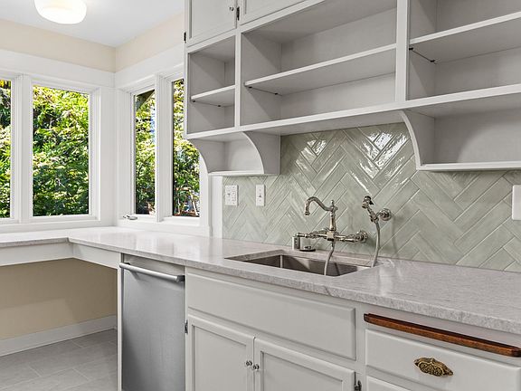 Gorgeous herringbone tile backsplash, honed stone counters and drop in sink in fresh and new kitchen remodel.