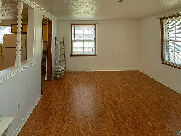 Another living room view showing the access to the kitchen on the left, the side window wall directly in front, and the window onto the front porch. The front door is on that wall, but is not in this photo.