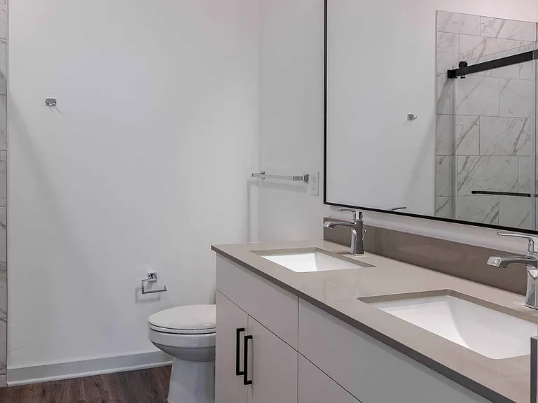 Primary bathroom with a dual-sink quartz vanity and a glass-enclosed walk-in shower with marble-style tile. Primary bathroom with a dual-sink quartz vanity and a glass-enclosed walk-in shower with marble-style tile.