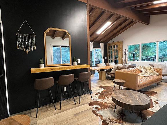 Stylish bar area with three stools and a large mirror, perfect for makeup prep or casual seating. The space is bright with adjustable lighting, blending comfort and functionality in the cabin''s open-concept design.