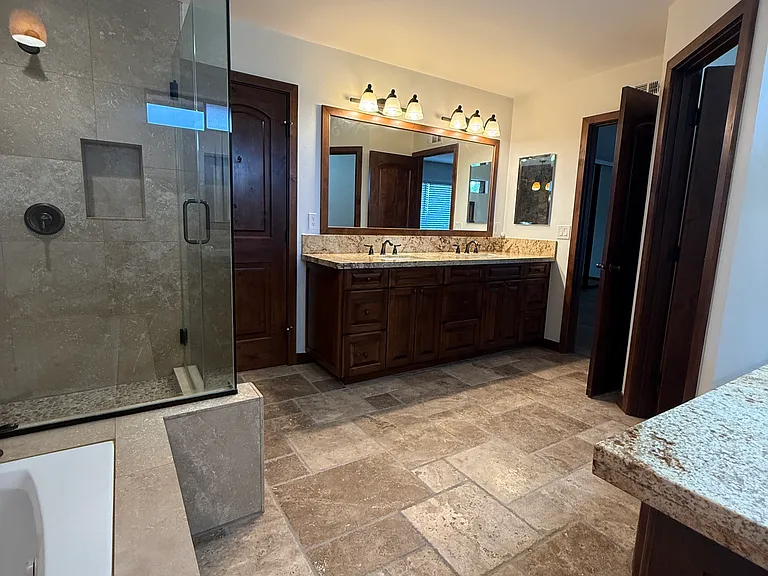 Spa like primary bathroom with jetted tub, glass enclosed shower, vanity, dual sinks, and direct access to walk in closet!