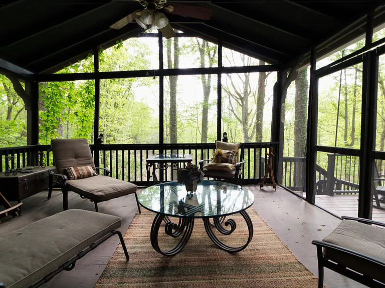 screened porch with wooded view off of deck and speak easy room