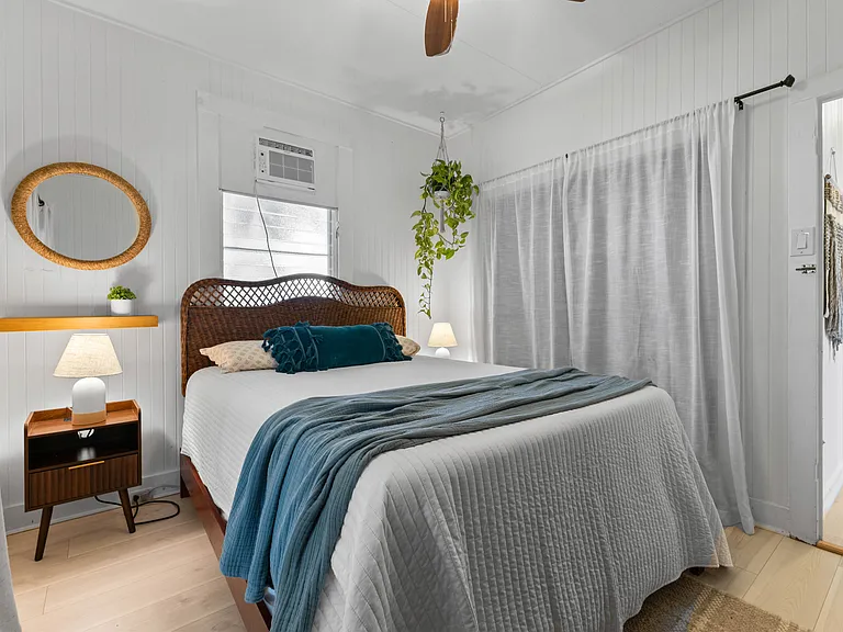 Front bedroom with queen bed, side tables, dresser, AC, ceiling fan, window and large closet with built-in shelving. French doors open to enclosed lanai.
