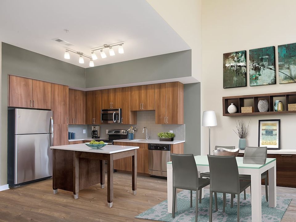 Upgraded dining area and kitchen with walnut cabinetry, white quartz countertops, light grey tile backsplash, stainless steel appliances, and hard surface flooring