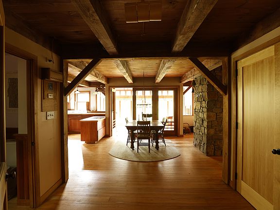 Entry into main living space, with the dining area and greenhouse in the center, kitchen to the left, and living room around the corner to the right