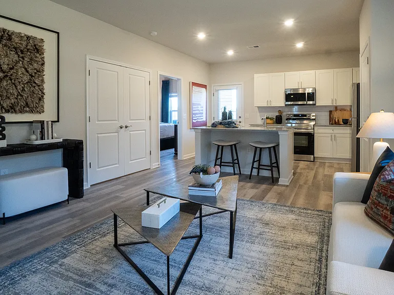 Spacious and open-concept layout. Showing the living room looking into the kitchen and primary bedroom off to the left.