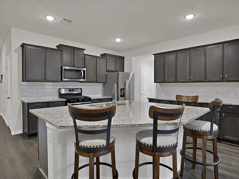 Kitchen with dark brown cabinetry, beautiful backsplash, and stainless steel appliances