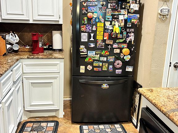 Kitchen area with ample cabinetry, granite-look counters, and full-size refrigerator for everyday meal prep and storage.