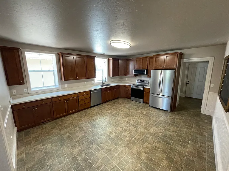 Large Eat-in Kitchen with expansive countertops and newer stainless LG appliances - french door refrigerator, dishwasher, range and slimline microwave. Back door entrance mudroom with with laundry is ahead.