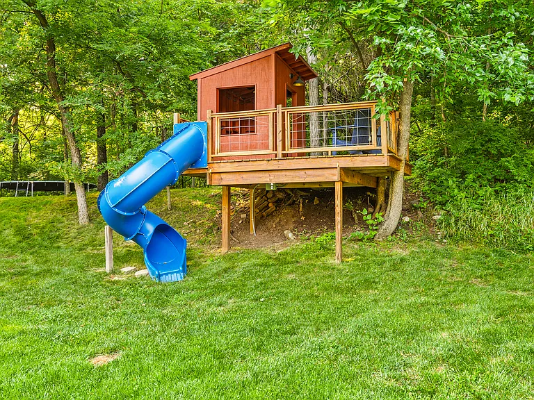 Awesome treehouse with a slide and patio for the kids to get outside and play in the backyard.