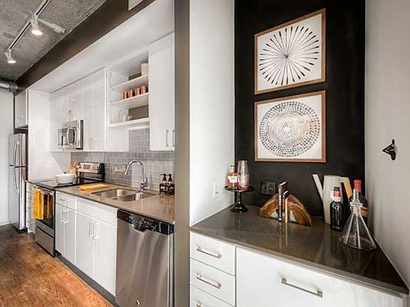 Kitchen with white cabinetry, quartz countertops, stainless steel appliances, tile backsplash and hard surface flooring