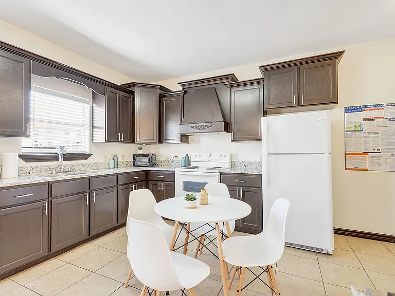 Kitchen space in Merida Vista Apartments showcasing a white refrigerator, microwave, and a dining table