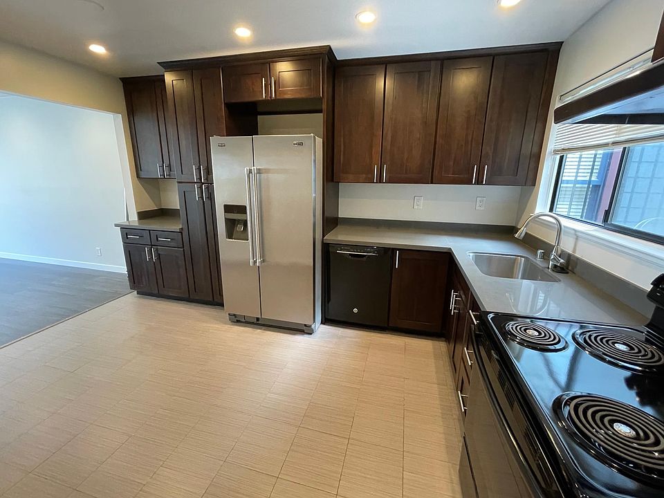 Large eat in kitchen with stainless steel and black appliances. Tile floor