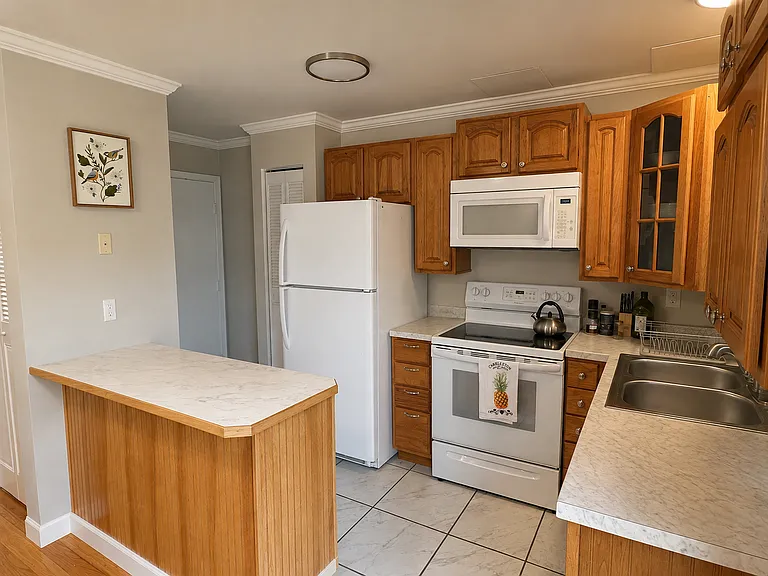 Kitchen with oak cabinets, ceramic tile floor, and a pass-through counter to the living room