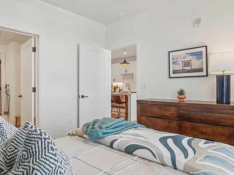 Enjoy a calming bedroom retreat featuring contemporary furnishings, warm wood tones, and easy access to adjoining living spaces and storage.