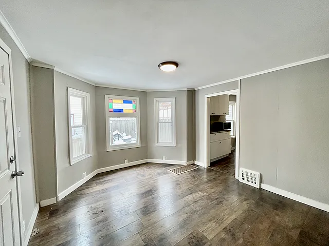 Living room with laminate plank flooring, original stain glass window, and vinyl replacement windows