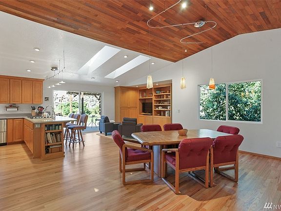 Delight in this "Great Room" style open-concept kitchen / family room / dining room, accented by warm hardwood floors, a vaulted natural wood ceiling, skylights and views onto the deck and beautiful back yard. The skylights open and will auto-close when rain is detected.