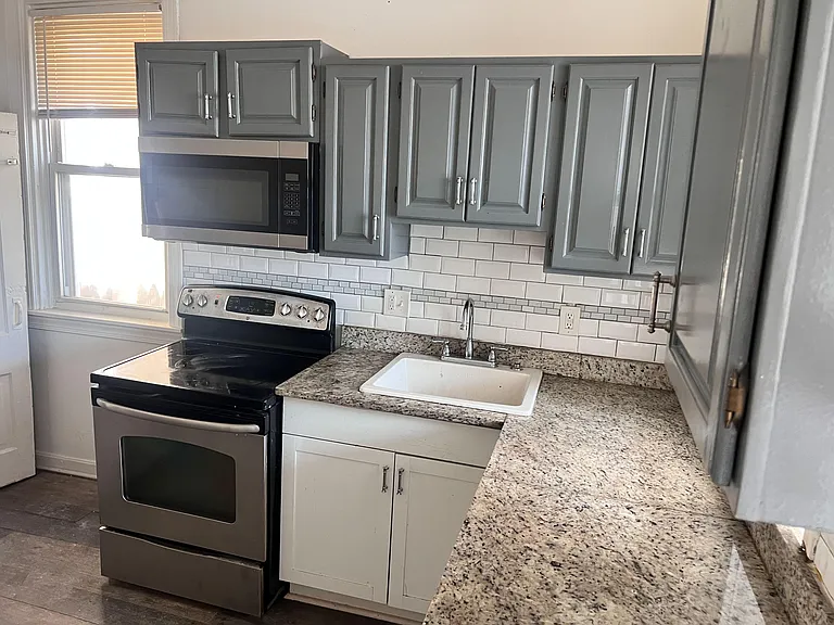 Efficient kitchen with granite-look counters, subway-tile backsplash, ample cabinets, and stainless range with over-the-range