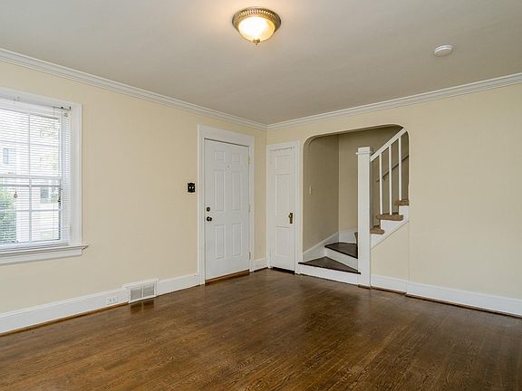Living room. View of entryway door and stairs.