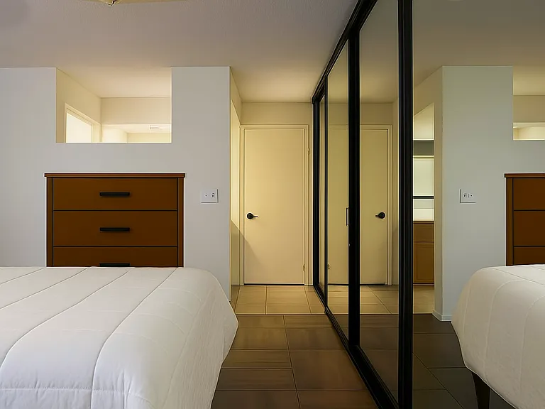 The master suite has wood like porcelain tile and mirrored sliding doors that span the entire wall. Furniture not included.