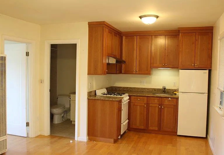 The kitchen is equipped with a cabinets with granite countertop, a gas range and a refrigerator.