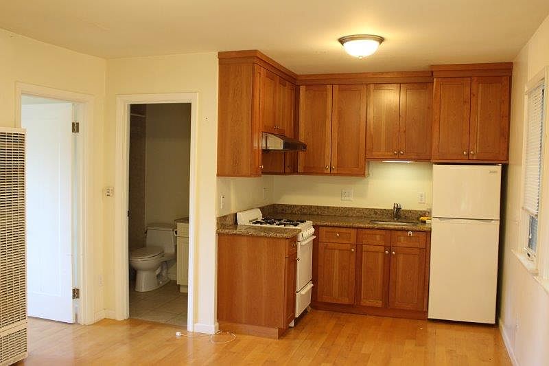 The kitchen is equipped with a cabinets with granite countertop, a gas range and a refrigerator.