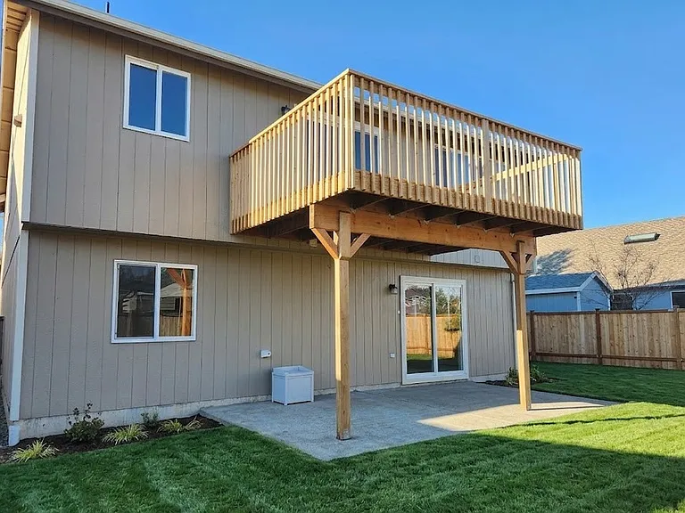 Covered patio with upper deck overlooking fully fenced backyard.