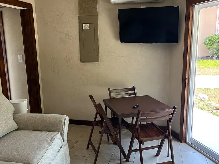 Compact dining nook with a four-seat table, tile flooring, wall-mounted TV, and direct access to the patio.