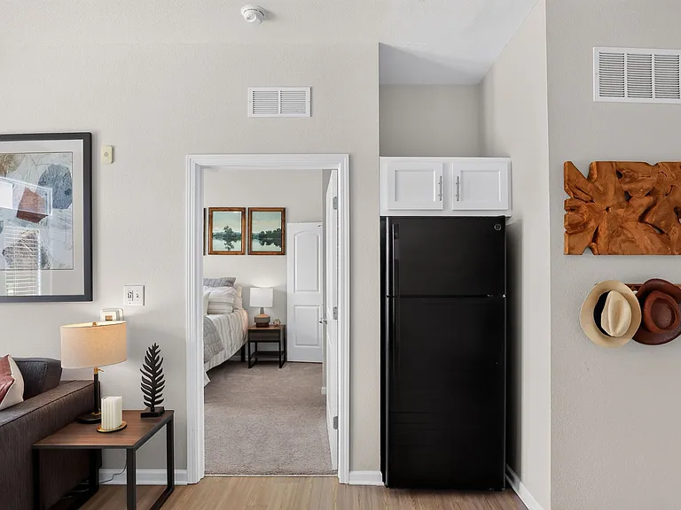 Modern apartment interior with a cozy living area leading into a stylish bedroom, featuring elegant wall art and contemporary decor.